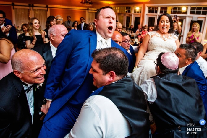 Photo by: <a href="https://www.wpja.com/contests/2018-v15/best-wedding-photographers/2318601">Michelle Arlotta - Milford New Jersey</a> Bear Brook Valley NJ | Wedding Reception Photograph of the bride and groom lifted in chairs at the reception.