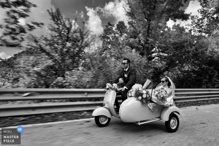 Foto von: <a href="https://www.wpja.com/contests/2018-v16/best-wedding-photographers/2328021"> Danilo Coluccio - Siderno Reggio Calabria </a> Hochzeits-Shooting mit Reggio Calabria-Paaren, die in einem Nebenauto Moto-Roller / Moped / Motorrad fahren