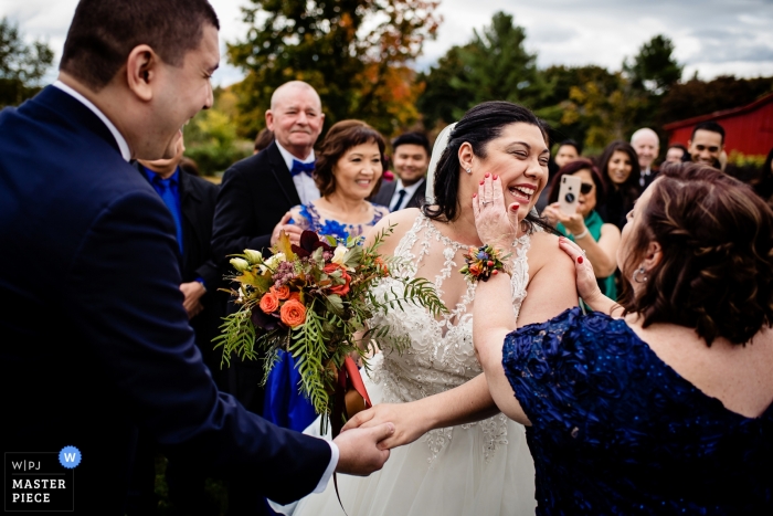 Picture of a bride having lipstick wiped off her cheek by a top Charlotte, Vermont wedding photographer