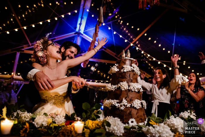 Foto: <a href="https://www.wpja.com/contests/2018-v16/best-wedding-photographers/2328371"> Jacob Hannah - Lincoln Vermont </a> Hochzeitsshooting mit Putney, Vermont Paar, als sie ihren Kuchen schneiden, bevor die Gäste zujubeln