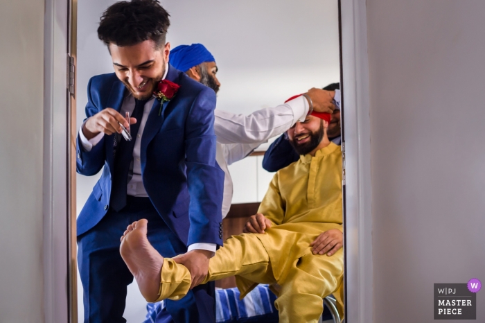 Photo by: <a href="https://www.wpja.com/contests/2018-v16/best-wedding-photographers/2328951">Jay Hoque - Uxbridge London</a> Wedding pictures of the groom getting help into his ceremony clothing - London photographer