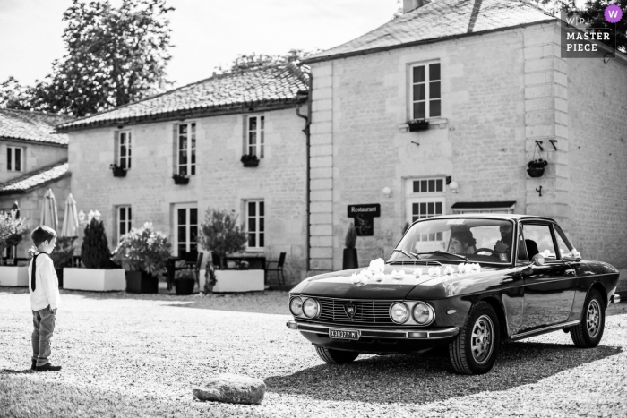 Foto von: <a href="https://www.wpja.com/contests/2018-v17/best-wedding-photographers/2334986"> Florent Fauqueux - La Rochelle </a> Ankunft des Autos des Bräutigams vor einem bezaubernden kleinen Jungen - Domaine du Greffier in Granzay-Gript FRANKREICH - Hochzeitsfotograf in La Rochelle