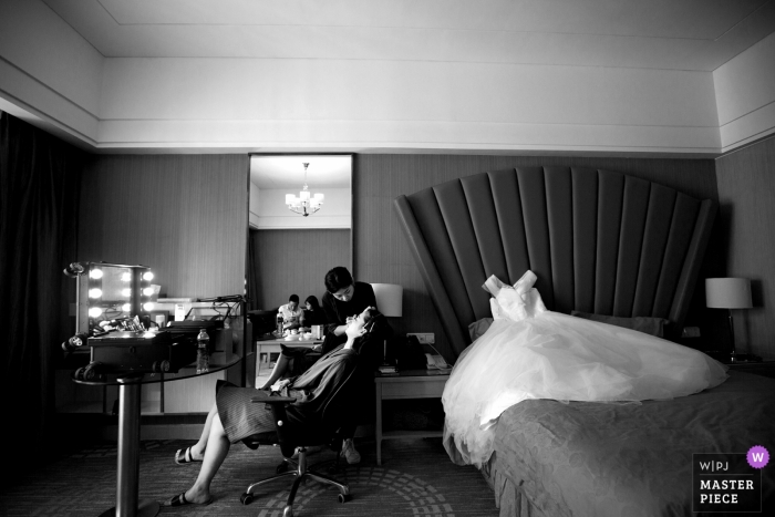 Zdjęcie: <a href="https://www.wpja.com/contests/2018-v17/best-wedding-photographers/2337711"> Zhongkun Zhang - Sanming </a> Dokumentalna ślubna fotografia w Fujian panna młoda otrzymywa twarzowego traktowanie i makeup z jej suknią kłama na łóżku