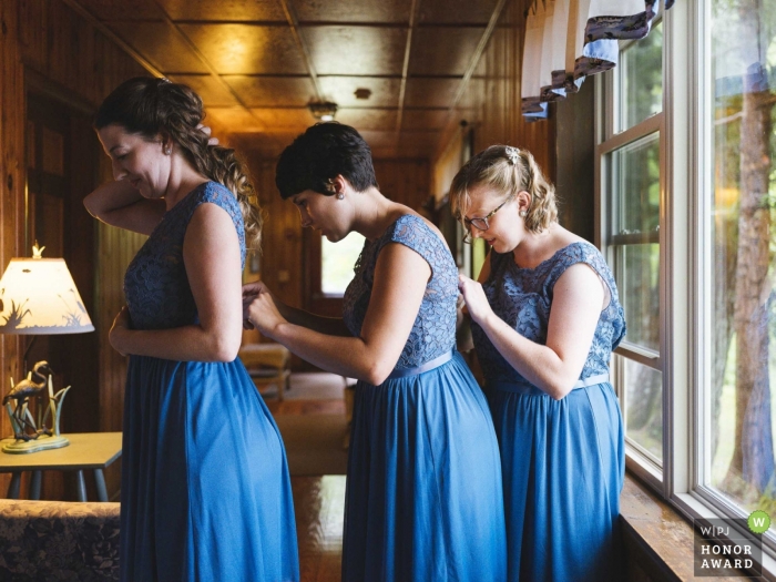 Foto: <a href="https://www.wpja.com/contests/2018-v17-Fotowettbewerb/Best-wedding-Photographers/2338816"> Corey Butler - South Portland Maine </a> Dokumentarisches Hochzeitsfoto von Brautjungfern, die jedes andere Kleid im Alamoosook Lakeside Inn in Orland, ME reparieren
