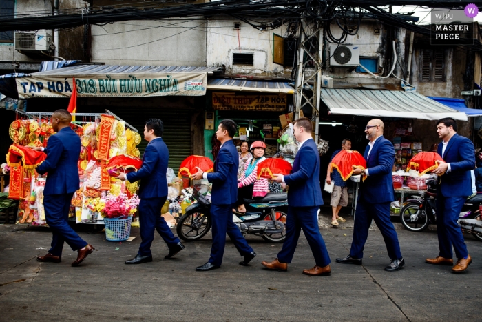 Huwelijksfotojournalism in Ho Chi Minh van groomsmen die enig dossier onderaan een straat van Vietnam lopen