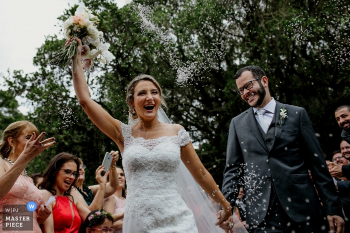 Zdjęcie: <a href="https://www.wpja.com/contests/2018-v17/best-wedding-photographers/2342871"> Renan Radici - Porto Alegre Rio Grande do Sul </a> Obraz ślubny z parą Rio Grande do Sul reagującą uśmiechem na prysznice konfetti w Sítio da figueira
