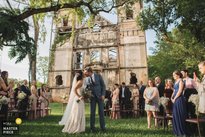 Photo: <a href="https://www.wpja.com/contests/2018-v17/best-wedding-photographers/2343366"> Wander Menezes - Belo Horizonte dans le Minas Gerais </a> Fazenda Jagoara Velha - mariage dans le Minas Gerais d'un couple s'embrassant lors d'une cérémonie en plein air sous les drees sur l'herbe