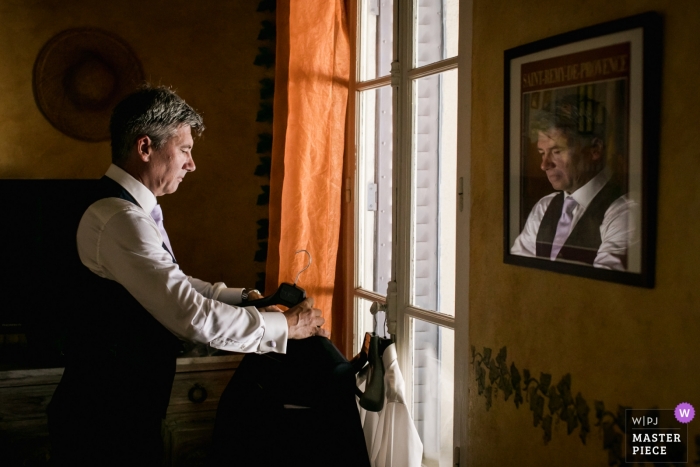 Photo by: <a href="https://www.wpja.com/contests/2018-v18/best-wedding-photographers/2351086">William Lambelet - Montpellier </a> Wedding pictures by Oppedette, France photographer | Getting ready wedding photograph of groom reflected in the glass of a framed image on the wall