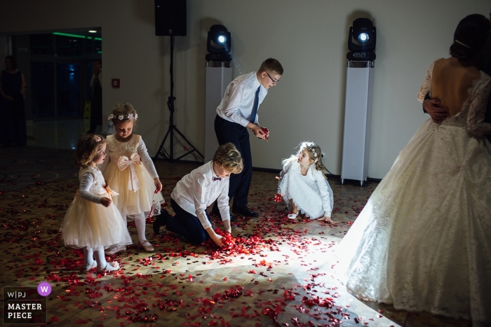 Zdjęcie: <a href="https://www.wpja.com/contests/2018-v18/best-wedding-photographers/2351471"> Martin Almasi - Zvolen </a> Słowacja fotoreportaż ślubny obraz pary tańczącej z dziećmi zbierającymi płatki kwiatów z parkietu.