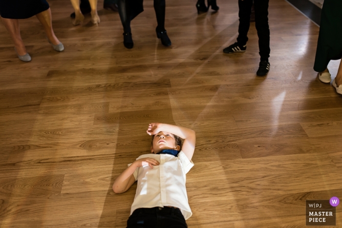 Photo by: <a href="https://www.wpja.com/contests/2018-v18/best-wedding-photographers/2351861">Katarzyna Mrugala - Gdańsk Pomorskie</a> Documentary wedding photograph of young boy lying on his back one the dance floor in Poland, Gdansk