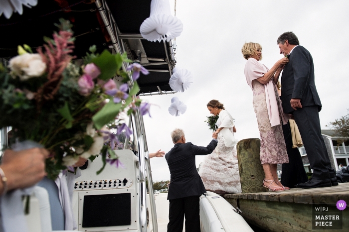 Photo by: <a href="https://www.wpja.com/contests/2018-v18/best-wedding-photographers/2352686">Matt Theilen - South Lake Tahoe California</a> Wedding pictures of bride loading into boat by nantucket, massachusetts photographer