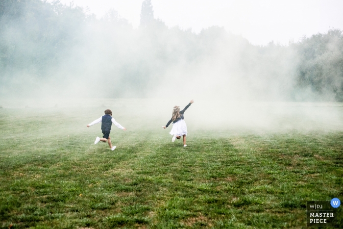 Wedding picture of kids running in field of smoke by Loire-Atlantique photographer