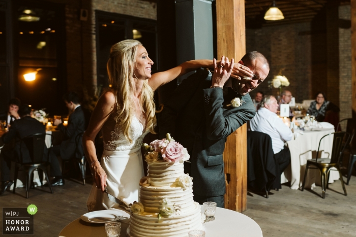 Photo by: <a href="https://www.wpja.com/contests/2018-v18-photography-competition/best-wedding-photographers/2355791">Noelle Adams - Chicago Illinois</a> Artifact Events Chicago | Picture of a couple smashing cake by a top Chicago wedding photographer
