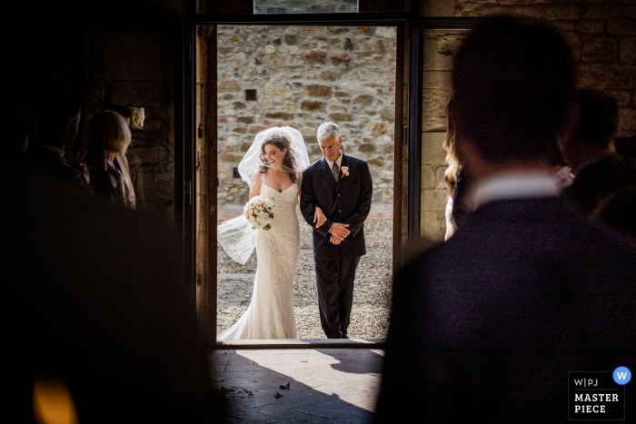 Photo by: <a href="https://www.wpja.com/contests/2018-v18/best-wedding-photographers/2357736">Andrea Sampoli - Siena</a> Photo of the bride and her father entering the Florence, Tuscany church for the wedding.