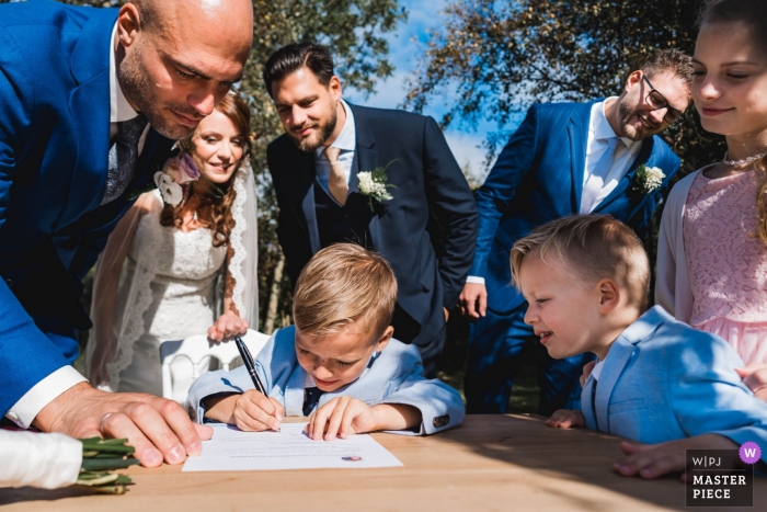 Foto por: <a href="https://www.wpja.com/contests/2018-v18/best-wedding-photographers/2358621"> Natalja van Ommeren - Zwartewaal Zuid Holland </a> Foto de boda con la pareja Zuid Holland después de su ceremonia al aire libre con niños pequeños que firman el certificado de matrimonio