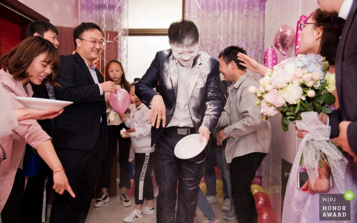 Photo: <a href="https://www.wpja.com/contests/2018-v18-photography-competition/best-wedding-photographers/2358781"> Lei Zhao - Ville de Weinan </a> Ville de Weinan, province du Shaanxi, Chine, lors du match de bienvenue, le meilleur homme a essayé de trouver des bonbons avec sa langue dans la farine sur la plaque. En conséquence, un ami à côté de lui a touché la plaque et a renversé le visage du meilleur homme