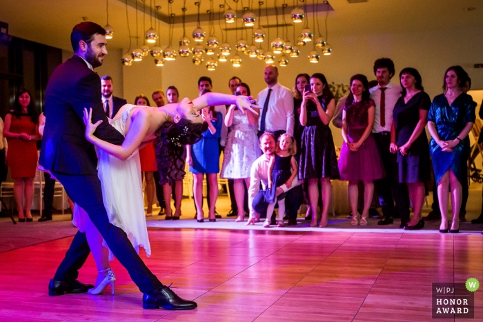 Couple de Bucarest lors de leur première danse devant leurs invités sous des lumières roses et violettes