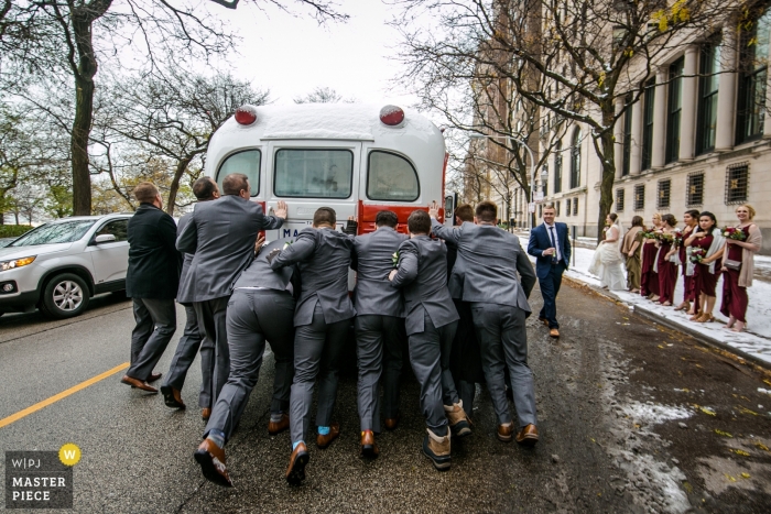 Photo by: <a href="https://www.wpja.com/contests/2018-v18/best-wedding-photographers/2360571">Milan Lazic - Chicago Illinois</a> Wedding picture of groomsmen pushing bridal party bus by Chicago photographer