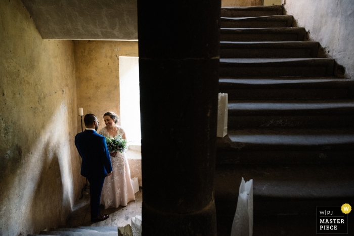 Photo by: <a href="https://www.wpja.com/contests/2018-v18/best-wedding-photographers/2362616">Lukas Powroziewicz - Edinburgh Midlothian</a> Neidpath Castle, Peebles, Scotland documentary wedding photo of a bride and groom sharing a private moment in the stairwell after the ceremony
