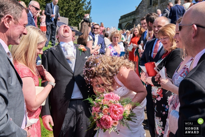 Foto: <a href="https://www.wpja.com/contests/2018-v18-Fotowettbewerb/Best-wedding-Fotografen/2364021"> Ian Bursill - Loughborough Leicestershire </a> Wymeswold, Leicestershire, UK Hochzeitshooting mit einem Paar umgeben von Gästen unter Konfetti-Dusche