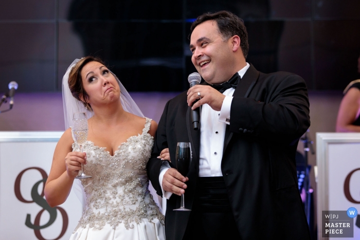 Photo de: <a href="https://www.wpja.com/contests/2018-v18/best-wedding-photographers/2364651"> John Zich - Chicago, Illinois </a> Photo de l'université de Loyola montrant les mariés pendant les toasts de la réception de mariage.