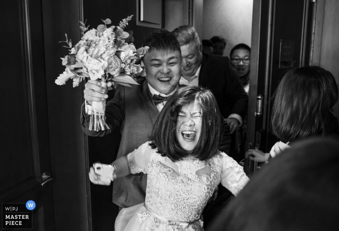 Photo by: <a href="https://www.wpja.com/contests/2018-v19/best-wedding-photographers/2366626">Peng Zhang - Beijing </a> Beijing documentary wedding photo of very excited bride entering room with bouquet