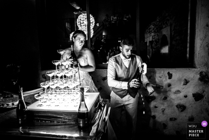 Foto door: <a href="https://www.wpja.com/contests/2018-v19/best-wedding-fotografen/2371436"> Julien Roman - Parijs </a> Fotograaf van het de huwelijksfotojournalistiek van Parijs van een paar ongeveer om champagne in de glastoren te gieten