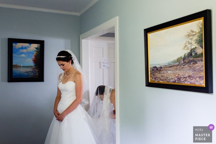 Photo by: <a href="https://www.wpja.com/contests/2018-v19/best-wedding-photographers/2377356">Kate Crabtree - Bangor Maine</a> MDI, Maine wedding photograph of bride getting help with veil.