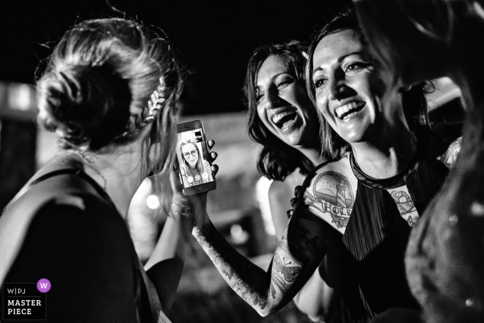Photo by: <a href="https://www.wpja.com/contests/2018-v19/best-wedding-photographers/2377941">Elena Haralabaki - Nea Ionia Attica</a> Mykonos, Greece wedding photograph of guests using facetime or Skype on a phone