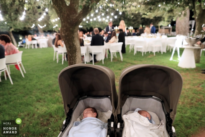 Foto door: <a href="https://www.wpja.com/contests/2018-v19-photography-competition/best-wedding-photographers/2378536"> Marco Odorino - Monopoli Bari </a> Huwelijksfoto van twee baby's in kinderwagens bij openluchtontvangst onder bomen in Puglia