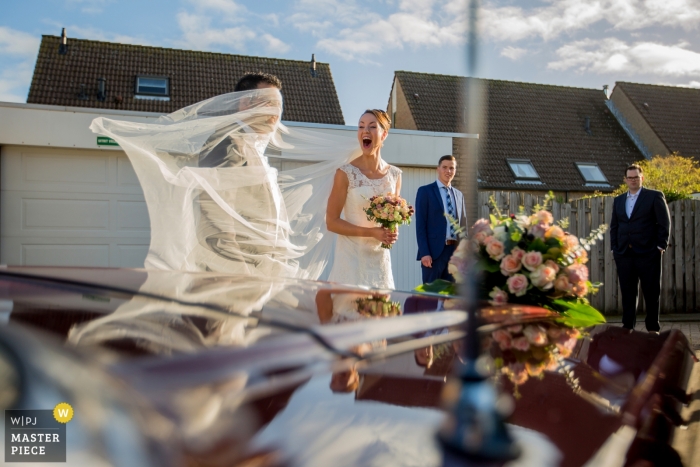 Photo by: <a href="https://www.wpja.com/contests/2018-v19/best-wedding-photographers/2379541">Gerhard Nel - The Hague Zuid Holland</a> Zuid Holland wedding photography of bride's veil and groom with wind and car reflections