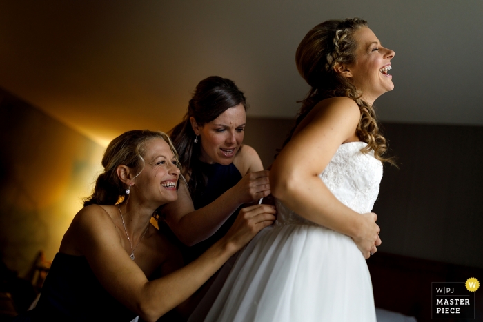 Photo by: <a href="https://www.wpja.com/contests/2018-v19/best-wedding-photographers/2380556">Travis Haughton - Chicago Illinois</a> Pictures of a bride getting helped into her dress - Grand Rapids wedding photographer