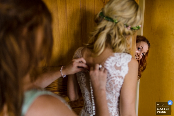 Hesse preparando la imagen de la novia recibiendo ayuda con su vestido | fotografia de bodas en alemania