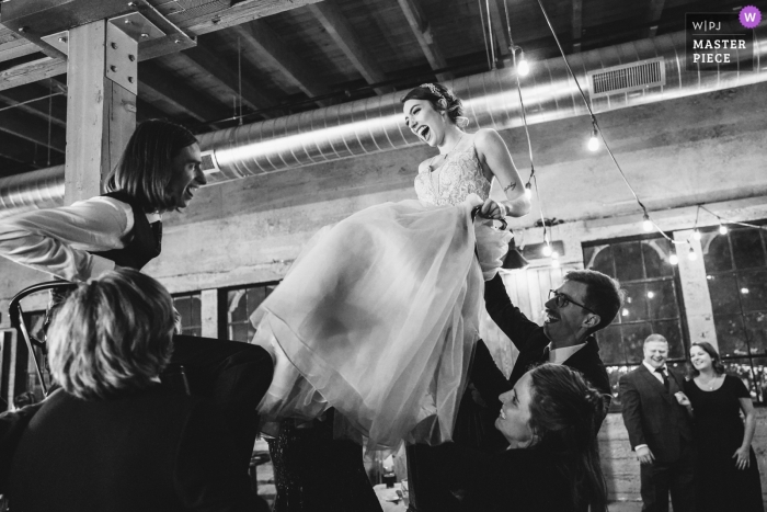 Wedding reception picture of bride and groom lifted in chairs by Seattle, Washington wedding photographer