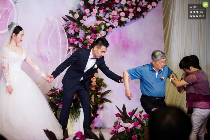 Foto: <a href="https://www.wpja.com/contests/2018-v20-Fotowettbewerb/Best-wedding-photographers/2389581"> Yifan Liu - Binhai New Area </a> Hochzeitstrieb während der Zeremonie auf Stadium mit helfenden Eltern der Tianjin-Paare