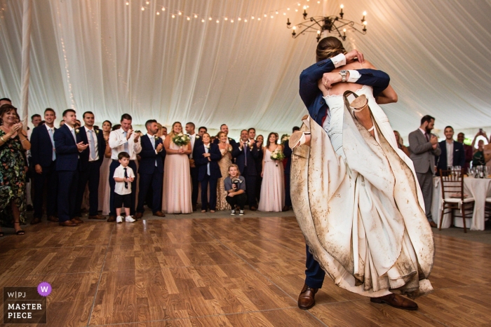 Noiva com um vestido de casamento muito sujo ser levantado pelo noivo na pista de dança dentro de uma recepção de tendas | Crossed Keys Inn | Fotografia de casamento de Nova Jersey