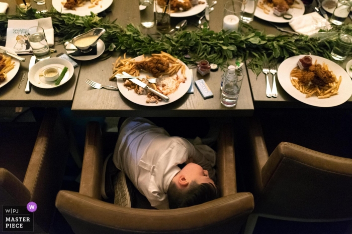 Foto da recepção de casamento em Chicago, Illinois, de um menino dormindo à mesa com comida