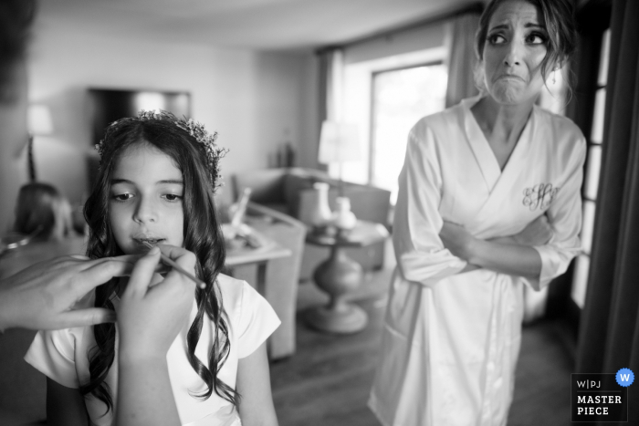 Una novia de Phoenix mira a la niña de las flores que tiene maquillaje aplicado durante la preparación de la imagen | Fotografía de boda AZ