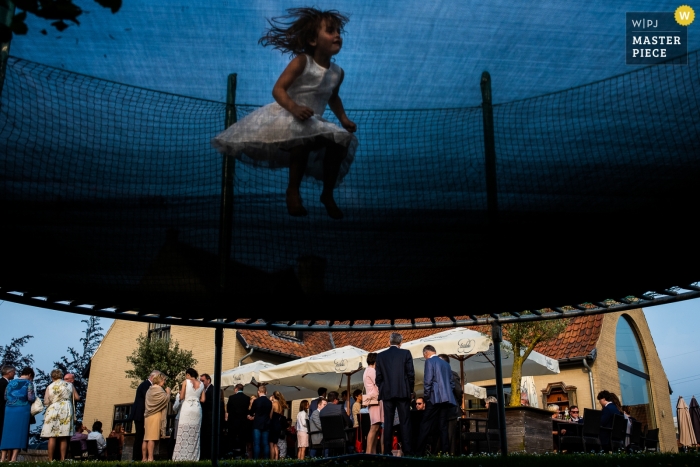 Photo by: <a href="https://www.wpja.com/contests/2018-v20/best-wedding-photographers/2398171">Ruth Wytinck - Landegem Oost-Vlaanderen</a> East Flanders wedding reception photograph of flowergirl jumping on trampoline