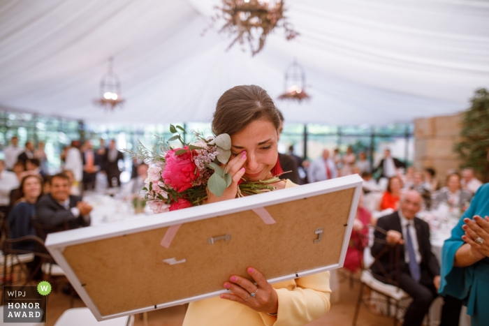 Foto: <a href="https://www.wpja.com/contests/2018-v20-Fotowettbewerb/Best-wedding-Fotografen/2400416"> Manuel Medrano Coll - Zaragoza Zaragoza </a> Hochzeitsfotoaufnahme während der Zeremonie in Saragossa - Berührter Gast, der ihr Geschenk betrachtet