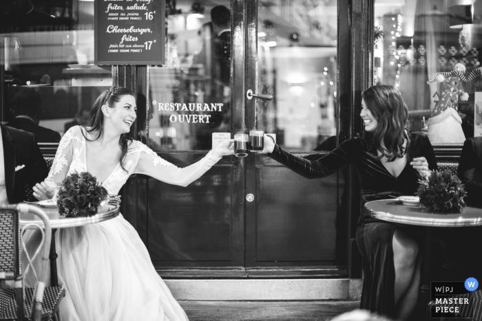 Photo by: <a href="https://www.wpja.com/contests/2018-v20/best-wedding-photographers/2403086">Simon Cassanas - Paris </a> Wedding photograph of bride toasting at coffee shop with girlfriend | Wedding day moments captured in Paris, France