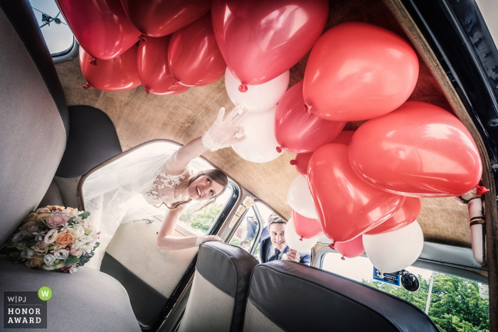 Huwelijksfoto van paar die limo met rode ballons in Venetië ingaan