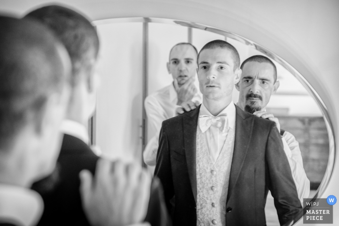 Fotografia de casamento em Veneza do noivo recebendo ajuda no espelho antes da cerimônia