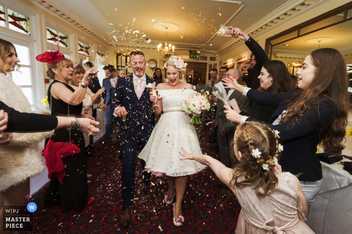 Bloemenmeisje en gasten gooien confetti naar bruid en bruidegom - Devon, Engeland Huwelijksceremonie in het Two Bridges Hotel