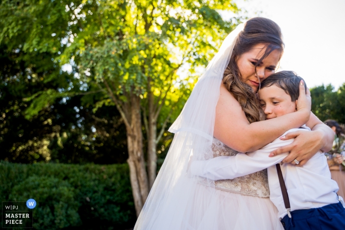 Foto: <a href="https://www.wpja.com/contests/2018-v20/best-wedding-photographers/2408826"> Joshua Grasso - Buford Georgia </a> Hochzeitsfotografie der Braut, die draußen Jungen umarmt | Hochzeitstagmomente in Atlanta, Georgia