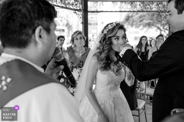 Foto: <a href="https://www.wpja.com/contests/2019-v01-Fotowettbewerb/best-wedding-photographers/2422131"> Omar Berr - Lima </a> Hochzeitsfoto vom Club de Playa Solimar - die hellen Küsse die Hand des Bräutigams während der Zeremonie - Hochzeitsfotograf aus Lima, Peru
