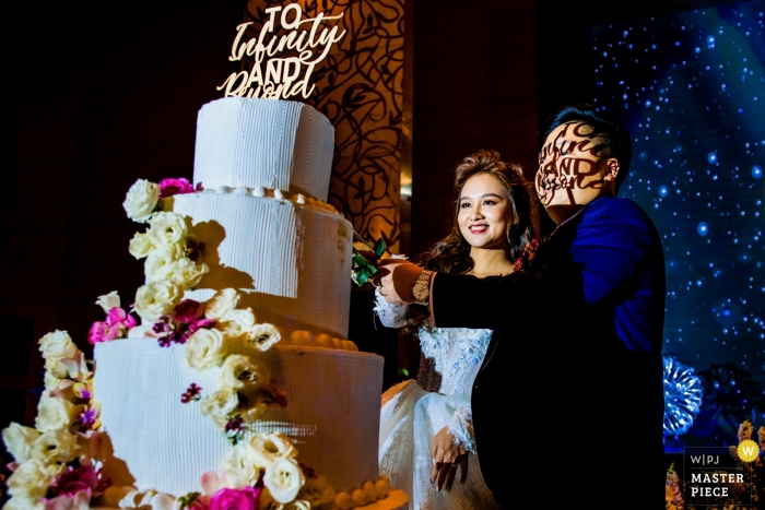 Ho Chi Minh wedding cake cutting ceremony - super groom transfiguration with "to infinity and beyond" shadowed on his face