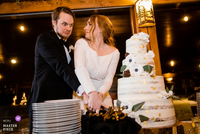 Foto: <a href="https://www.wpja.com/contests/2019-v01/best-wedding-photographers/2427851"> Jerome Pollos - Coeur d'Alene Idaho </a> Die Braut und der Bräutigam reagieren darauf, dass sie ihre Hochzeitstorte während ihres Empfangs im Elkins Resort am Priest Lake in Nordman, Idaho, fast umgestoßen haben.