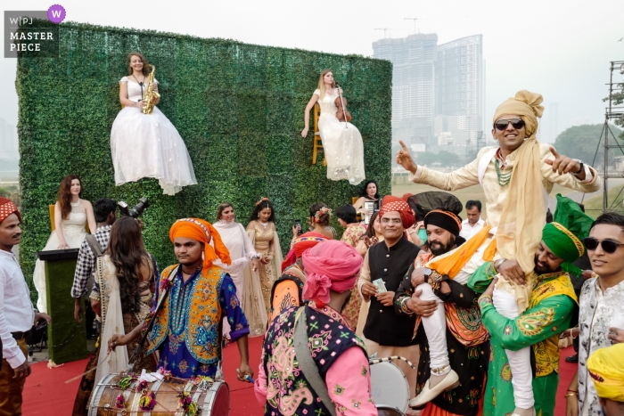 Photo by: <a href="https://www.wpja.com/contests/2019-v01/best-wedding-photographers/2429741">William Lambelet - Montpellier </a> Mumbai, India weddings - photograph of Groom arrival with musicians in chairs hanging on an ivy wall