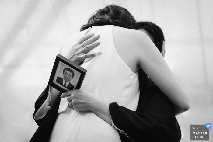 Foto door: <a href="https://www.wpja.com/contests/2019-v01/best-wedding-photographers/2431111"> Takafumi Iikura - Tokyo Tokyo </a> Otaki Rose Garden bruiloften - liefde vanaf de achterkant. Foto van de bruid knuffelen een Vrouw met een foto van een man